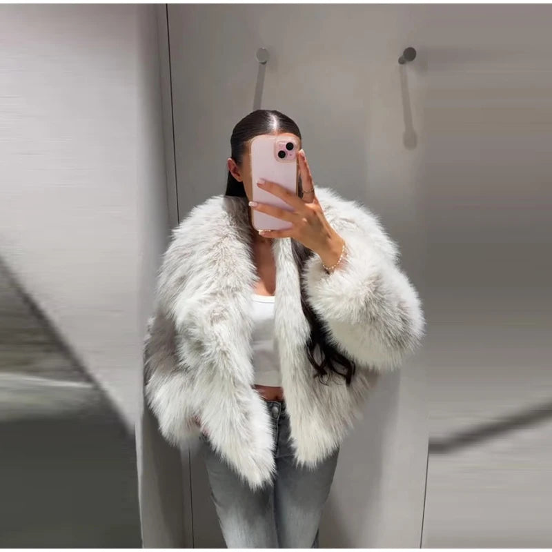 Person wearing a white fluffy jacket taking a mirror selfie.