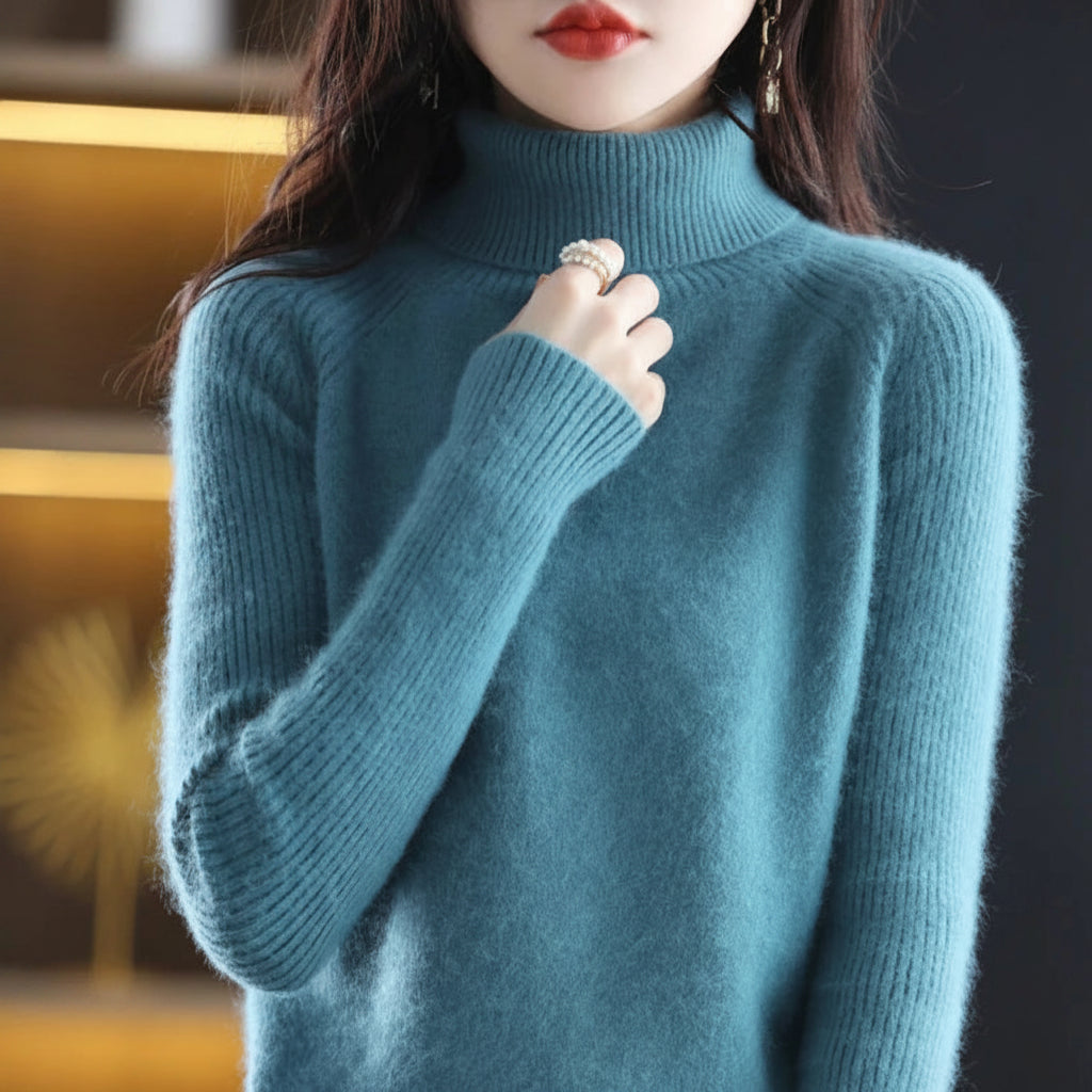 A woman wearing a fuzzy ribbed turtleneck sweater in a muted blue-green shade.