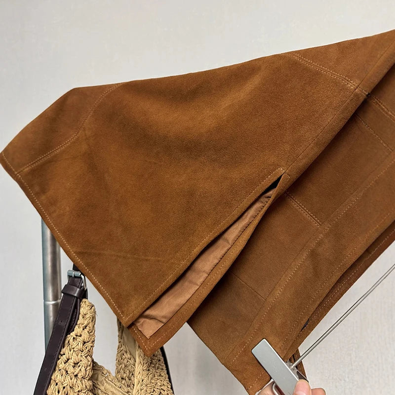 Brown fabric draped over a chair with a hand holding a knife, on a light gray background
