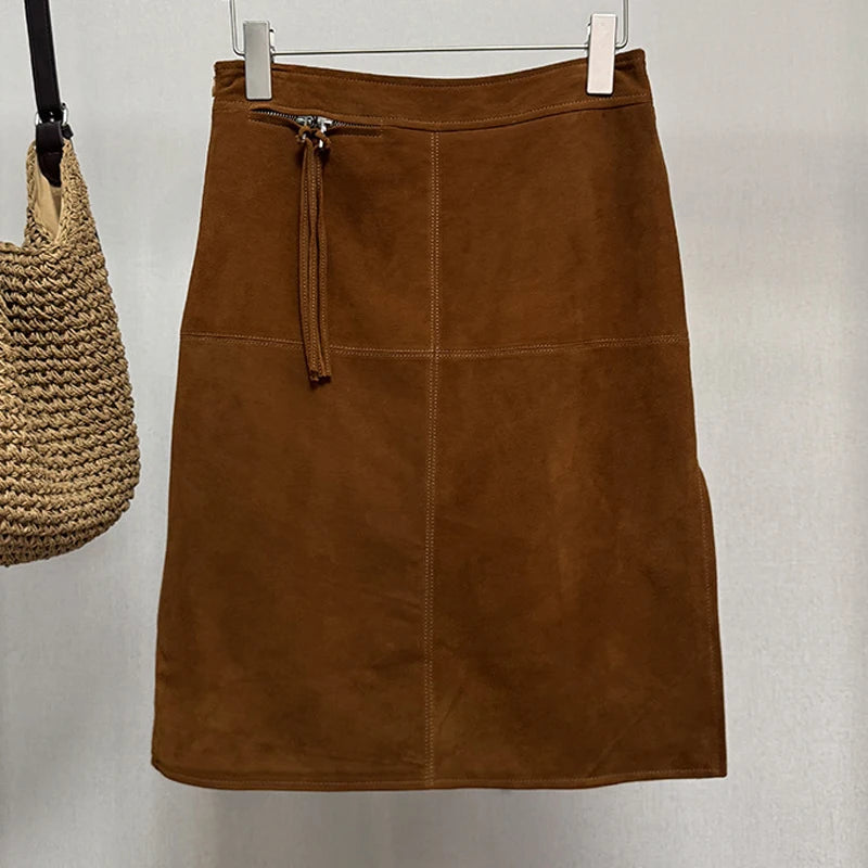 Caramel Brown suede skirt on a hanger with a woven bag beside it against a plain background