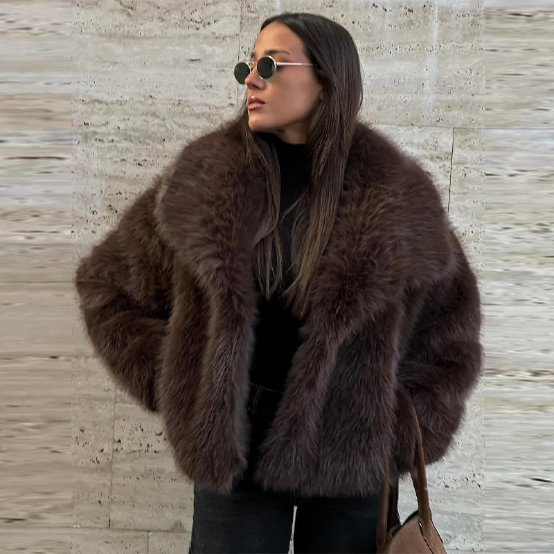 Woman wearing a brown fur coat against a textured wall.