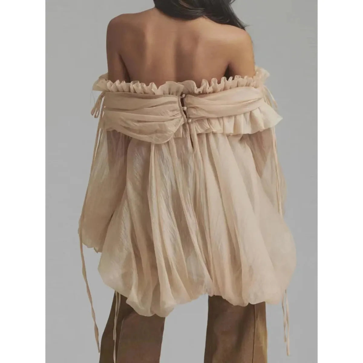 Buttoned Back Of Beige off-shoulder top with ruffled details on a plain background