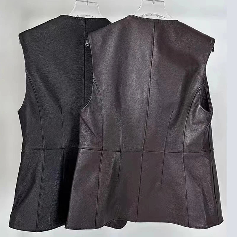 Two leather vests shown from the back, hanging on clear plastic hangers against a plain light background. One vest is black and the other is a very dark brown, both with a peplum-like seam detail at the waist.