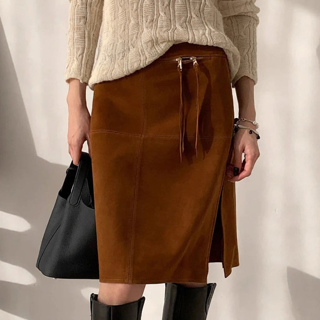Person wearing a brown suede skirt with a plain background