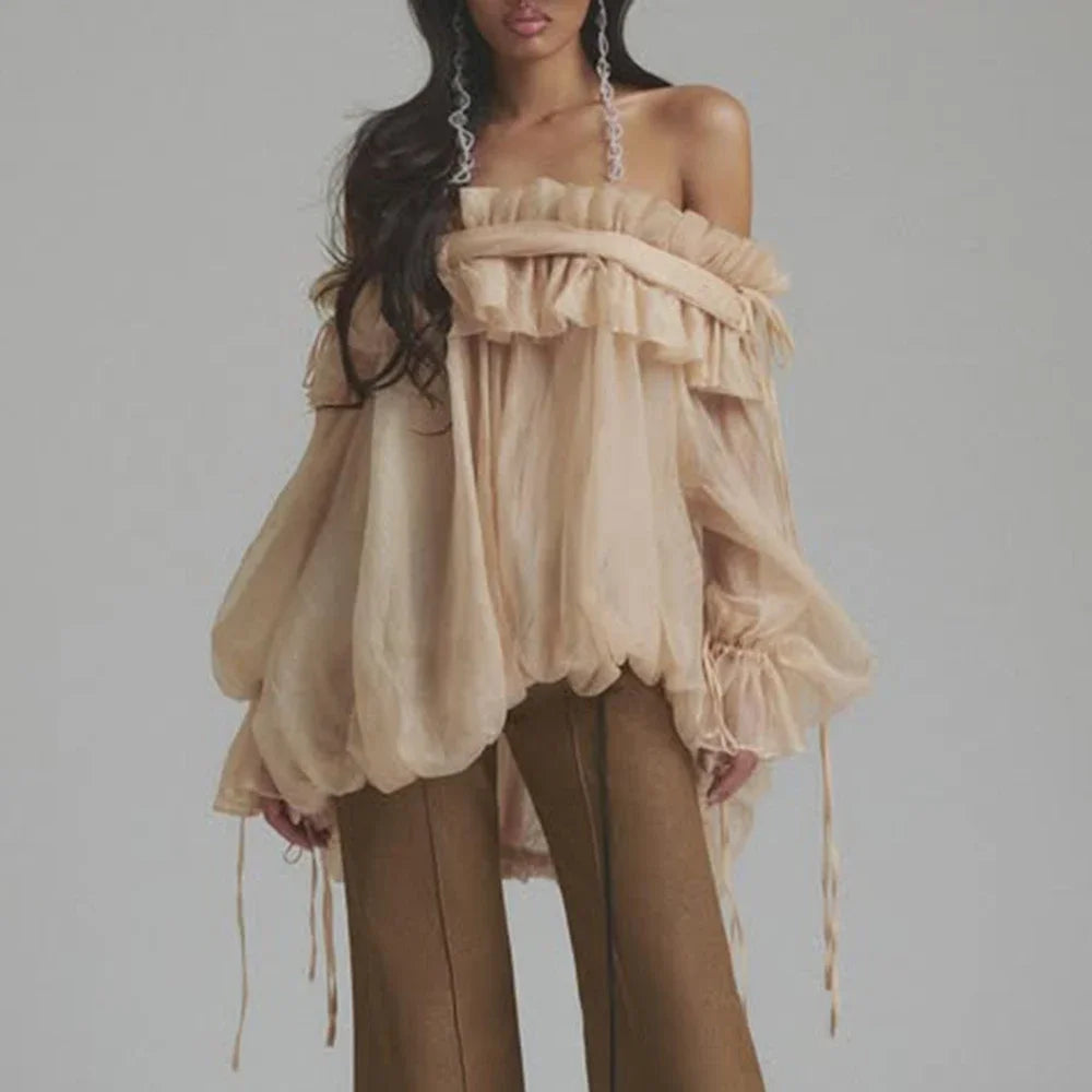 Woman wearing a beige off-shoulder top and pants against a gray background