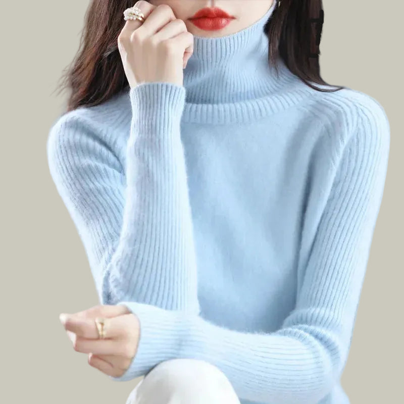 A woman wearing a light blue ribbed turtleneck sweater, who appears to be sitting down.