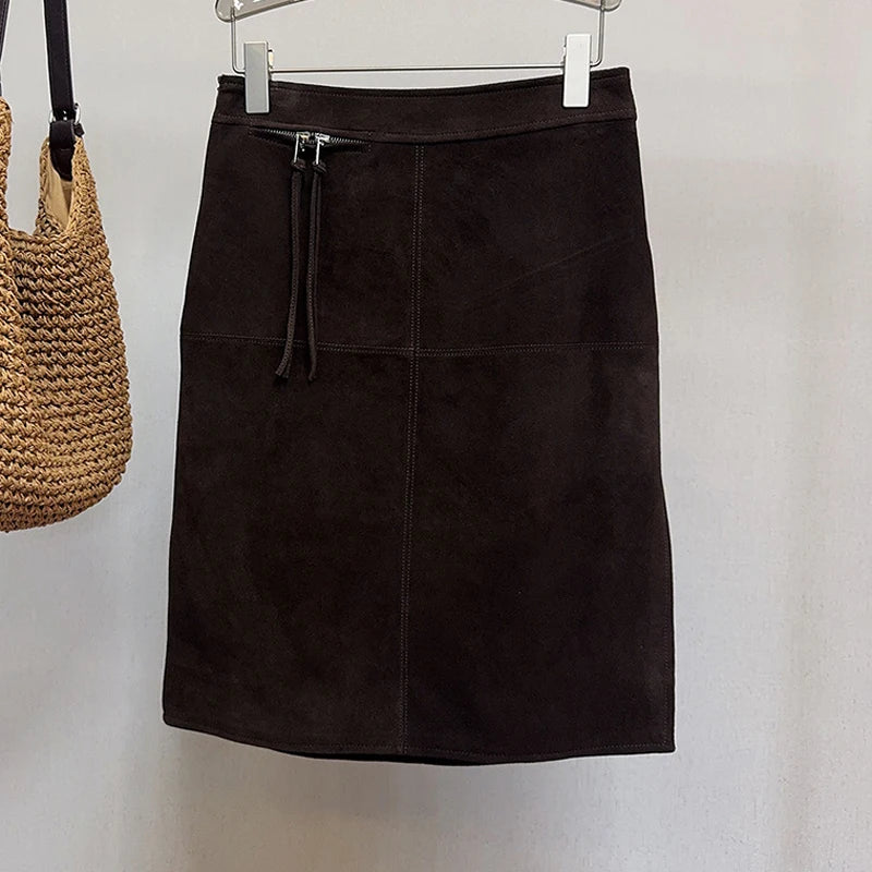 Deep Brown skirt on a hanger next to a woven bag against a white background
