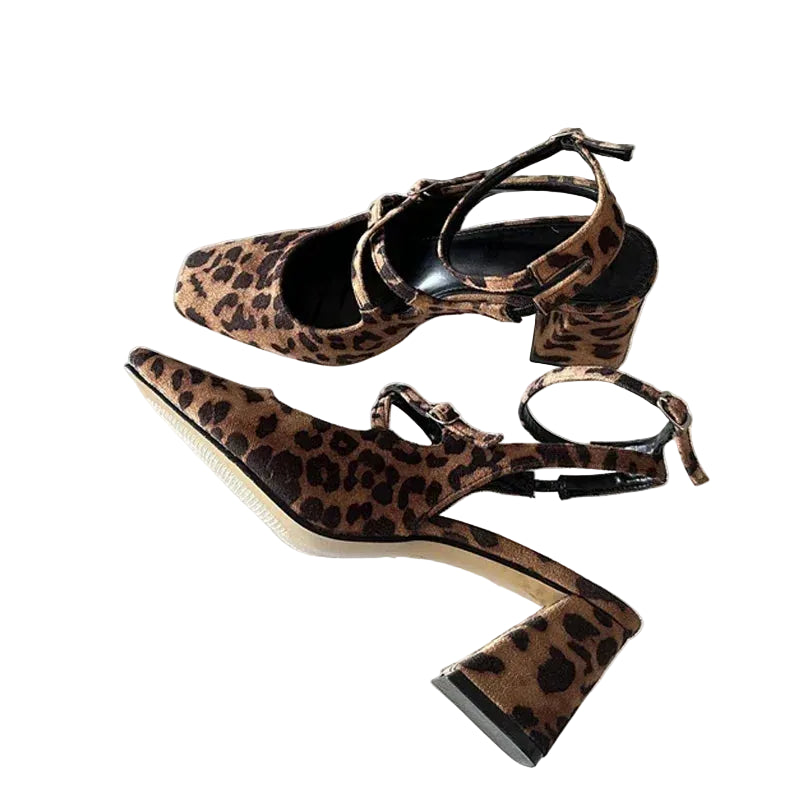 A pair of women's block-heel slingback sandals with a brown and black leopard print pattern, displayed on a reflective white surface.