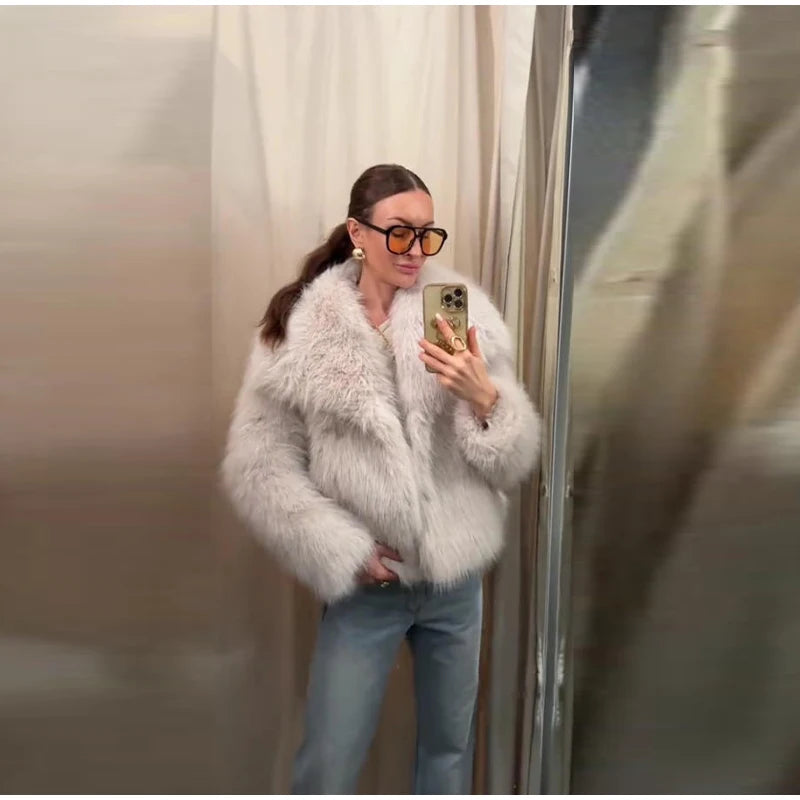Person wearing a fluffy white jacket and blue jeans taking a mirror selfie.